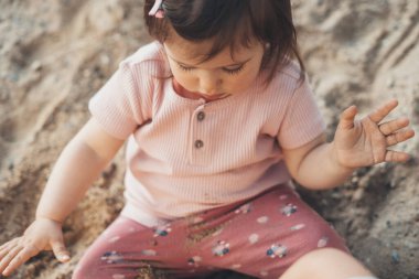 Close-up portrait of baby girl playing on the sand. Happy family outdoors. Travel concept. Nature concept. Family day concept.