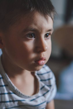 Close-up of a boys face staring intently at something in the house. Childhood concept. Natural chang emotional state