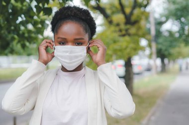 Copy space. Young African-american woman putting covid-19 protective face mask before entering the office. Outbreak disease prevention. Medical health. Virus