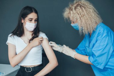 Female doctor administrating COVID-19 Vaccine to a caucasian patient at the hospital. irus, epidemic, disease. Medical healthcare. Medicine medical health.