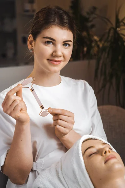 Beautician showing the jade roller to the camera, presenting the procedure he is going to do. Facial beauty. Natural skin care cosmetic. Health care, beauty