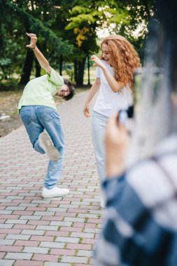The girl and the boy went out to the park to make videos to post, posing as they showing half-hearted with their fingers. Gen Z talent people play video