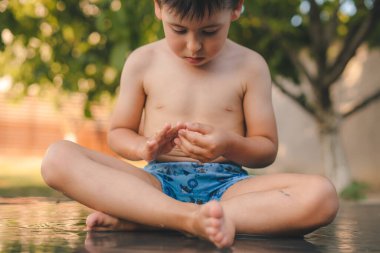 Wet funny little boy playing with water in sunny backyard. Summer vacation fun. Sunny day. Happy family outdoors. Summer outdoor fun activity.