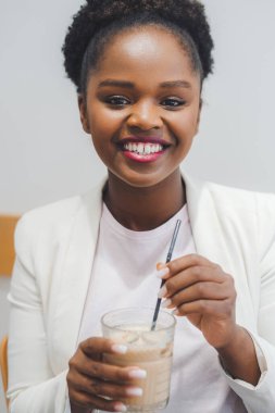 Close-up front view portrait of african-american businesswoman drinking a soft drink in the cafe. Woman beauty face. Business portrait.