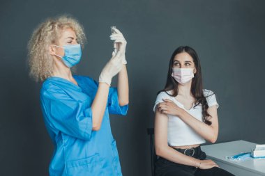 Curly woman doctor in white gloves and medical mask checking the syringe before vaccination. Virus, epidemic, disease. Medicine medical health. Pandemic