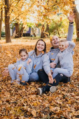 Portrait of a family posing together in an autumn city park, with yellow leaves around. Parent, child. Activity relationship. Smiling happy child. Happy family