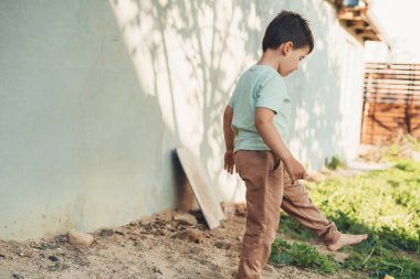 Boy stepping through the garden of the house, spending his vacation day active and interesting. Summer outdoors activity for kids. Summer sunny day.