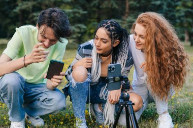 Beginner bloggers looking on the Internet how to shoot a video that will attract more followers. Concept of youth, tech, social and friendship. Group of friends
