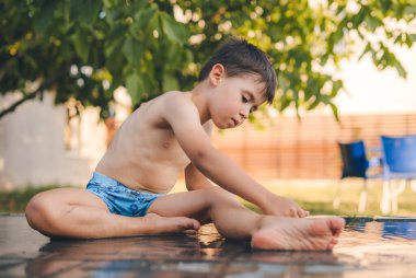 Boy cooling himself off with water after a hot summer day. Summer outdoors activity for family with kids. Party game for children. Healthy activity for hot