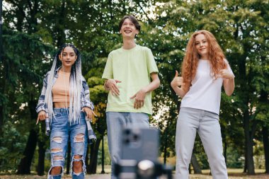Cute teenagers making hipster video, phone on selfie stick. A time of rest and entertainment. Hobby street