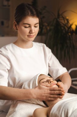 Beautiful Caucasian woman having spa massage of the head in beauty salon. Body care. Spa body massage treatment.