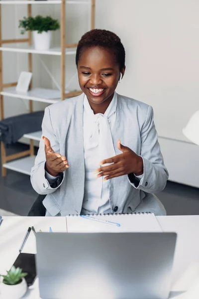 Happy beautiful young black woman speak at virtual consultation on laptop. Female freelancer sitting working computer. Business call. Distance education.