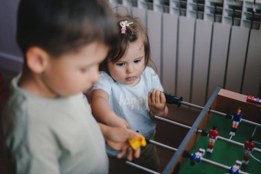 Two little kids learning by playing the wooden table football. Childhood concept. Soccer ball. Goal competition. Children play table games. Team sport.