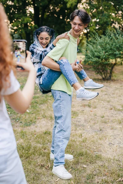 Teenage girl asking friends to make a movement when she filming creative video for her blog on social media. Blogger makes videoblog, blogging concept