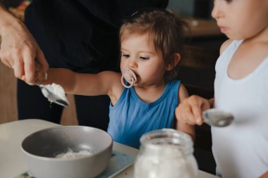 Annem ve iki çocuğu evde tatil sabahı pasta pişirirken pasta malzemesi hazırlarken eğleniyorlar. Hamur hazırlarken kasedeki malzemeleri karıştırıyorum.
