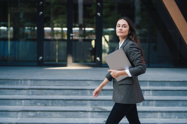 A brunette businesswoman walking in city street with laptop going to work in the morning. Copy space. Getting outside for a change. Businessman holding laptop