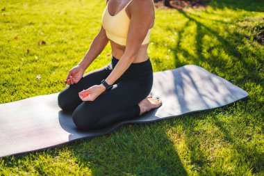 Yoga yapan bir kadının rahat koltukta poz verip yaz parkında meditasyon yaptığını görmek. Yoga egzersizi, esneme bacakları. Vücut şekli ve