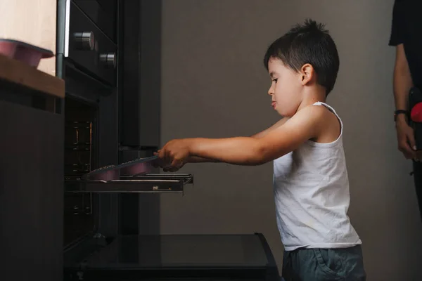 Αγόρι Προσπαθεί Βάλει Δίσκο Μπισκότα Στο Φούρνο Χωρίς Βοήθεια Της — Φωτογραφία Αρχείου