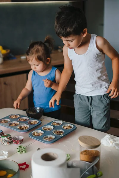 两个漂亮的孩子在厨房的桌上用新鲜的浆果装饰松饼 幸福的家庭 可敬的浆果甜点概念 — 图库照片