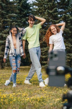 Yaz parkında dans eden dört komik arkadaştan oluşan bir grup tripod kullanarak akıllı telefondan bir video kaydediyor. Sosyal medya etkileyicisi