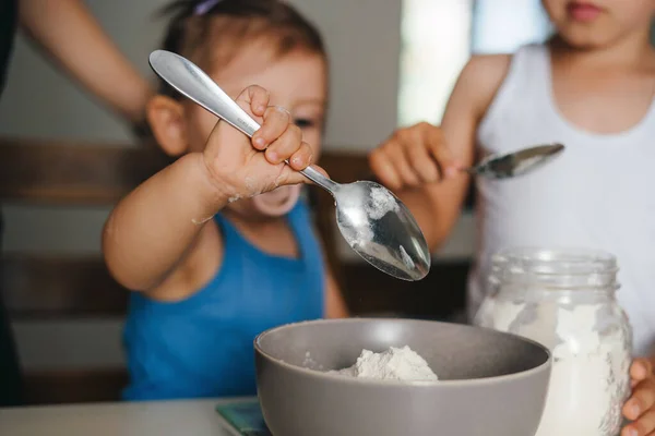 可爱的女婴在厨房做烘焙面包的面团时 用勺子配料加入碗中 准备自制的糕点 表达积极的情绪 — 图库照片