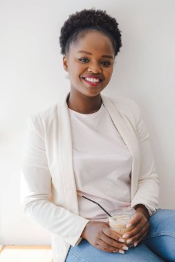 Kafede kahve içen ve kameraya gülümseyen genç bir kadının portresi. Güzellik portresi. Yemek molası..