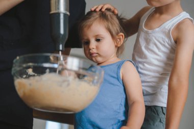 Aile hamur işlerini mutfakta birlikte pişirir, malzemeleri karıştırır: yumurta, un ve süt hamur yapar. Yaşam tarzı, ebeveynlik, aşçılık konsepti. Mutlu aile