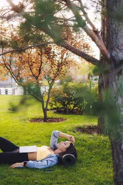 Spor Giyimli Güzel Bir Kadın Parkın Ortasında Çimlerin Üzerinde Kitap — Stok fotoğraf