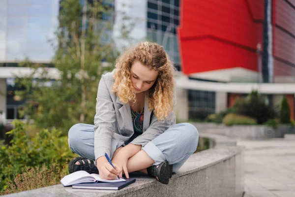 Caucasian woman university student with notebooks learning at campus yard. Beauty portrait. Young woman face portrait. Fashion model. People lifestyle.