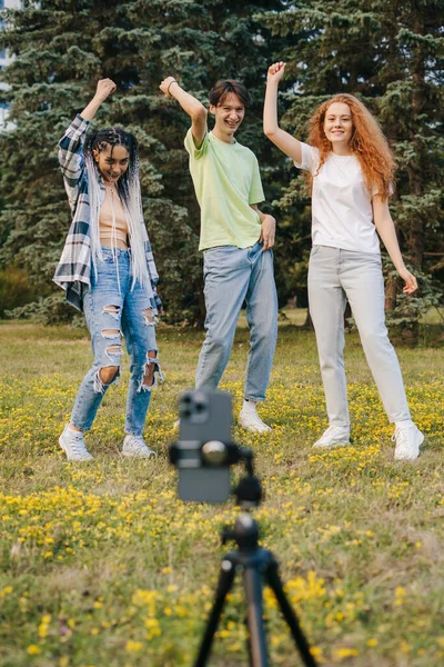 Teenagers are filming dance video with a phone in the summer park. Social media challenge. The concept of a dancer, influencer, social media artist.