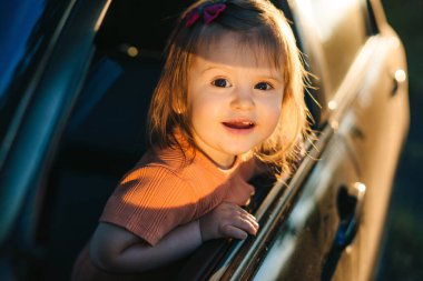 Arabadaki bebek pencereye bakıyor doğanın güzelliği karşısında hayrete düşmüş, güneş yüzünü ısıtıyor. Gülümseyen mutlu çocuk. Mutlu aile, çocukluk
