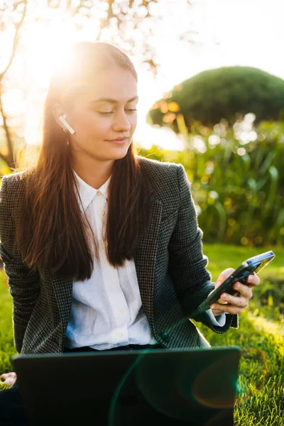 Επιχειρηματίας Κάθεται Στο Πάρκο Ελέγχοντας Smartphone Της Εργάζονται Φορητό Υπολογιστή — Φωτογραφία Αρχείου