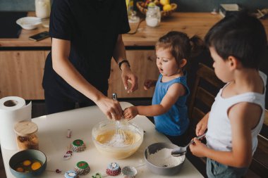 Mutfakta hamuru hazırlayan, kurabiye pişiren mutlu bir aile. Çocuklu bir aile sabahları mutfakta vakit geçiriyor..