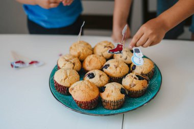 Çocuk ellerinin yakın plan çekimi yeni pişmiş keklerin son süslemesini yapıyor. Çocuk bakımı. Yemek konsepti. Tatlı yemek. Pişmiş keklerin tadı çok güzel.