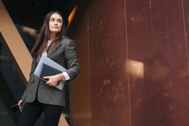 Dışarıda dizüstü bilgisayarı olan genç ve neşeli bir kadının portresi. İş başarısı.