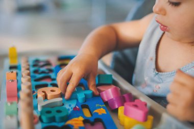 Yüksek sandalyede oturan sağlıklı bir kız bebek ve eğitici oyuncaklarla oynuyor. Bebek gelişimi. Erken çocukluk gelişimi kavramı.