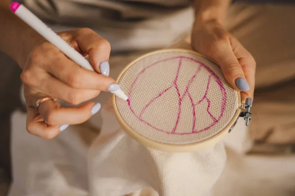 Embroidery in the hands of the woman, doing cross-stitch work by hand, drawing first of all the scheme on the canvas. Step by step. Work steps. Hobby, crafting
