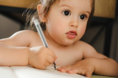 Evde oturup kalemle resim çizen komik, güzel bir kızın yakın plan portresi. Bebek gelişimi. Okul eğitimi. Küçük sanatçı