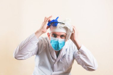 Şok olmuş doktor, elleri koruyucu maske ve beyaz laboratuvar önlüğü takıyor.