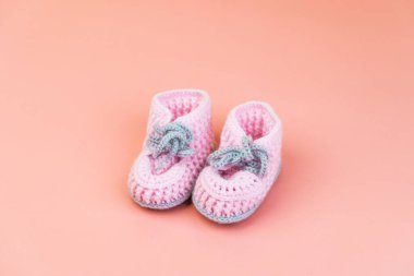 Pembe üzerine izole edilmiş prematüre bebekler için yünden yapılmış gri ayakkabı bağcıkları olan el yapımı pembe çizmeler.