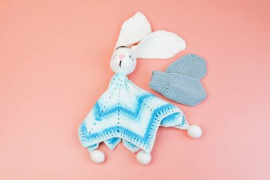 El yapımı mavi-beyaz tavşan oyuncakları ve prematüre bebekler için gri eldivenler pembe arka planda izole edilmiş prematüre bebekler için.