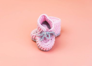 Pembe üzerine izole edilmiş prematüre bebekler için yünden yapılmış gri ayakkabı bağcıkları olan el yapımı pembe çizmeler.