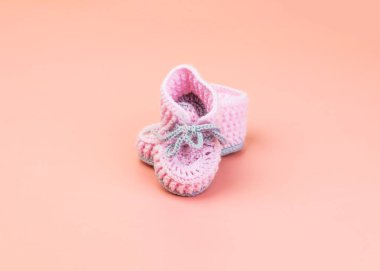 Pembe üzerine izole edilmiş prematüre bebekler için yünden yapılmış gri ayakkabı bağcıkları olan el yapımı pembe çizmeler.