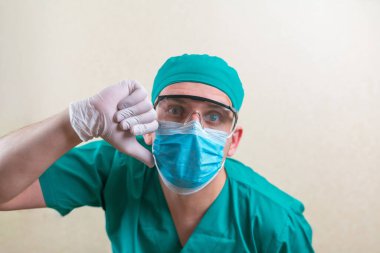 Yeşil cerrah kıyafetli ve sarı arka planda gözlüklü doktor izole edildi.