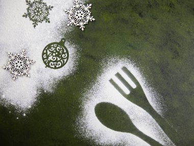 Un kar taneleri ve mutfak aksesuarlarıyla Noel ağacı yeşili arka plan. Noel tatili kurabiyeleri. Mutfak masasında un desenleri var..