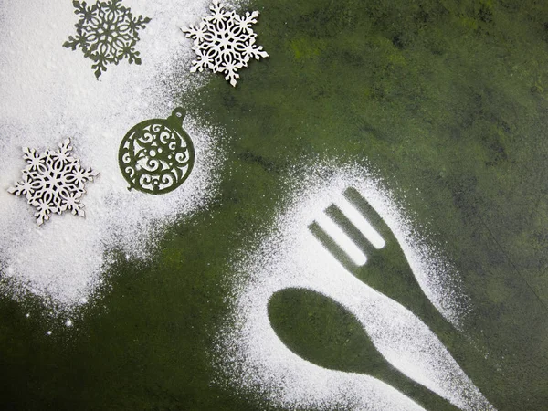 Un kar taneleri ve mutfak aksesuarlarıyla Noel ağacı yeşili arka plan. Noel tatili kurabiyeleri. Mutfak masasında un desenleri var..