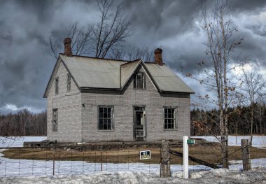 Kışın Kanada 'nın kırsal kesimindeki bir çiftlik bahçesinde terk edilmiş ürkütücü bir ev.