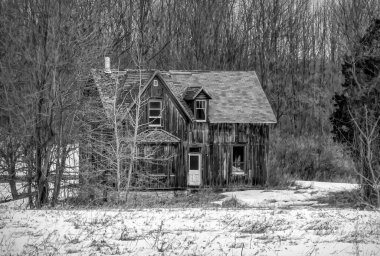 Eski siyah beyaz terk edilmiş ürkütücü görünümlü bir ev kışın Kanada kırsalındaki bir çiftlik bahçesinde