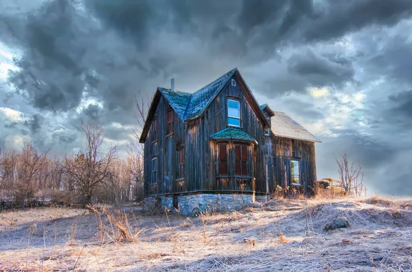 An old abandoned spooky looking house in winter on a farm yard in rural Canada