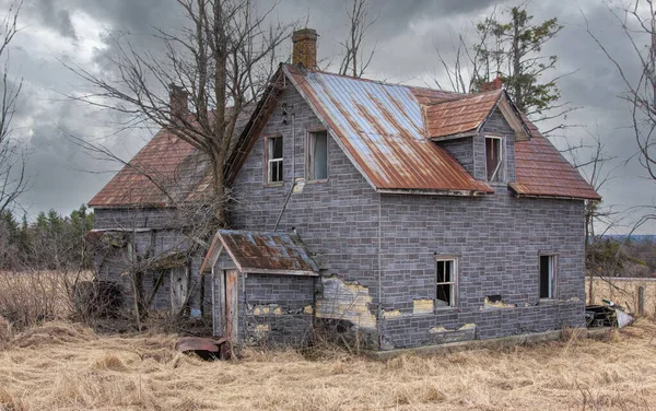 Baharda terk edilmiş ürkütücü bir ev Kanada kırsalındaki bir çiftlik avlusunda.